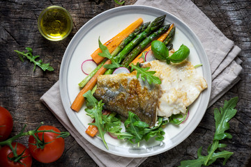 Fish fillet with vegetables on wooden background