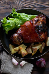 Roasted pork knuckle with fresh green salad and potato wedges