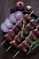 Close-up of uncooked shish kebabs with turkey hearts, above view