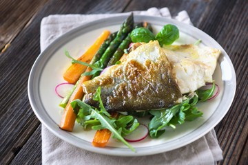 Fish fillet with vegetables on wooden background