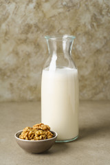 Fresh homemade walnut milk in a bottle with fresh walnuts