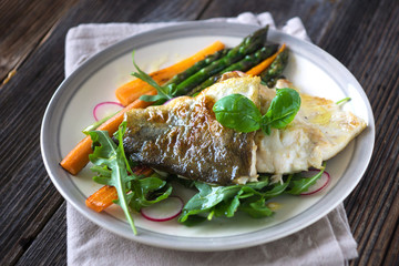 Fish fillet with vegetables on wooden background