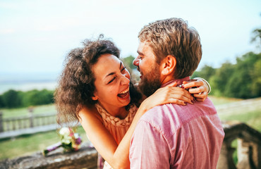 Happy couple on vacation. Lovers are laughing. Happy guy and girl. Lovers enjoy each other in the evening park. Man with beard. Girl with curley hair