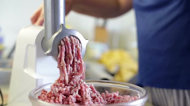 Woman making mince in the kitchen with meat grinder