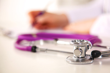 A medical stethoscope near a laptop on a wooden table, on white