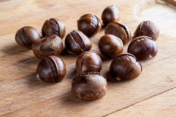 Chestnuts with shells on wooden cutting board