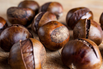 Chestnuts on wooden cutting board closeup from side