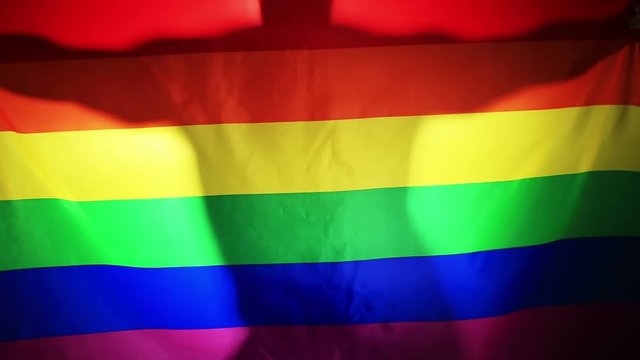 dancing silhouette of a man against a background of the flag of the LGBT community