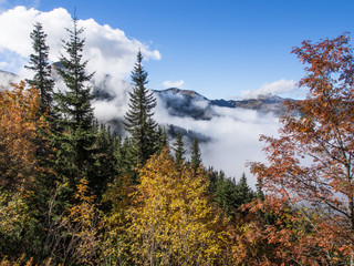 Wędrówka górska w słoneczny jesienny dzień, złota jesień w górach i chmury w dolinach