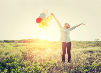 Happy beautiful young woman standing holding colorful of balloon