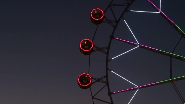 Close-up of Noria by rotating at night with large colorful of led lights and motion.Fast speed and stops.Time Lapse