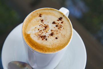 A cup of coffee in a white cup on glass background