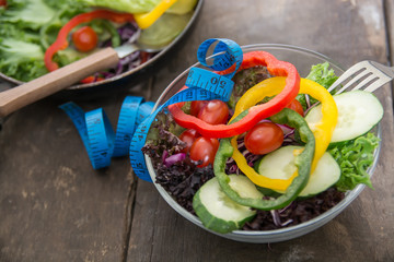 Fresh vegetables salad on  bowl with measuring tape over wooden