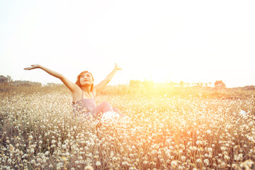 Sexy Beautiful woman sitting in flower field raising hands with