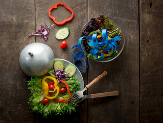 Fresh vegetables salad on bowl with measuring tape over wooden b