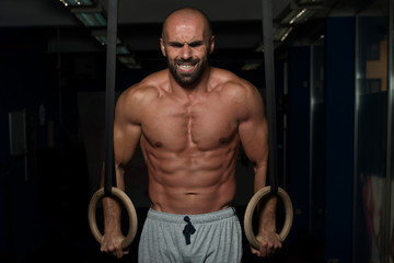 Fototapeta na wymiar Muscular Man Hold Gymnastic Rings