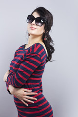 Fototapeta premium Beautiful brunette in sunglasses. Young girl in a striped dress 