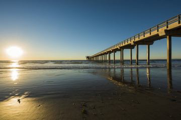 Fototapeta na wymiar Wide angle shot of Scripps Pier with reflection during sunset with sun in La Jolla, San Diego, California