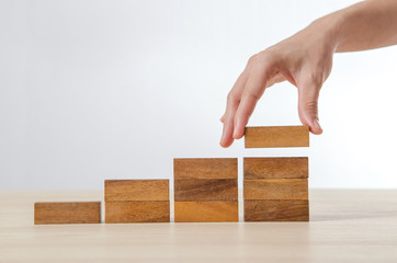 Close up Woman hand arranging wood block stacking as step stair. Business concept growth success...