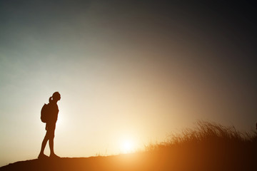 Silhouette of woman backpacking with sunset.