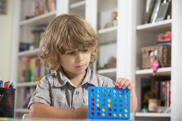 Litlle boy playing four in a row. Growing child's brain, cognitive and creative development, finding solutions, thinking