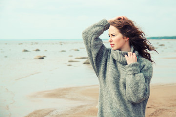 Attractive woman wearing a warm cardigan at the cold beach