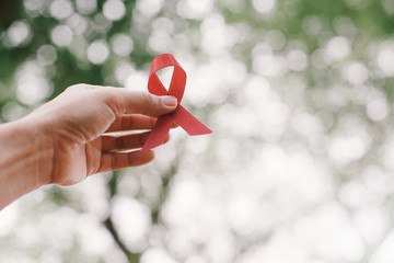 red aids ribbon in hand. - obrazy, fototapety, plakaty