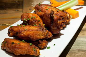 Spicy Buffalo wings with celery and carrots.