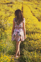 Naklejka na ściany i meble young girl walks among daisies in a spring field
