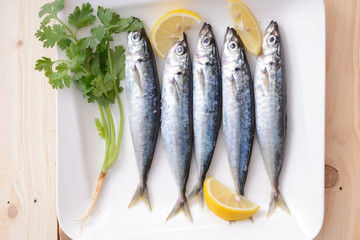 sardines with lemon wedges and parsley on white plate