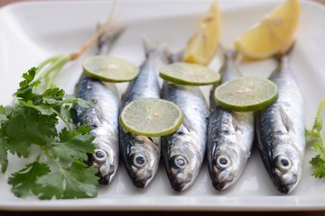 sardines with lime, lemon wedges and parsley on white plate