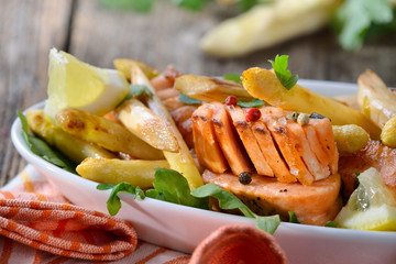 Gebratener bayerischer Spargel mit Lachsstreifen auf Rucolabett serviert - Roasted  white asparagus with fried salmon served on rocket leaves