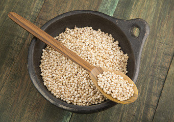 Pearl mijo in bowl and wooden spoon.