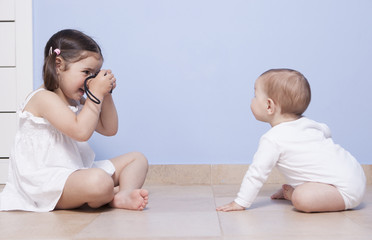 Pretty little sister taking pictures to her baby brother © WH_Pics