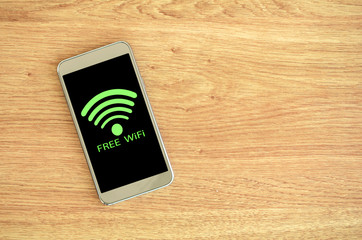 Smart phone on wood background with free Wifi sign.