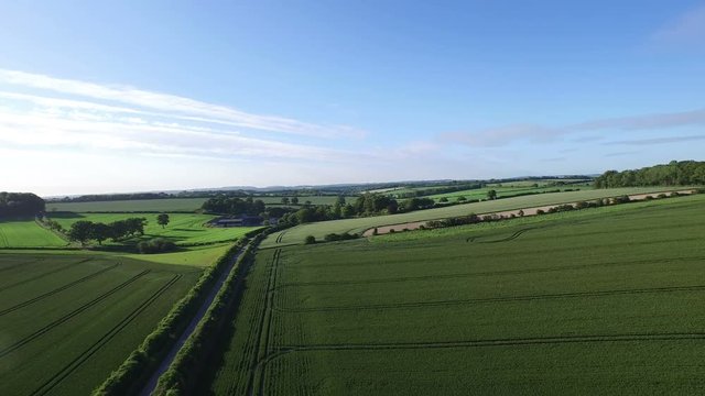  Aerial flight above rural road & fields in the English countryside. 