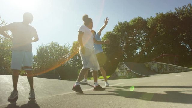  Happy young male friends, hanging out & dancing at skate park 