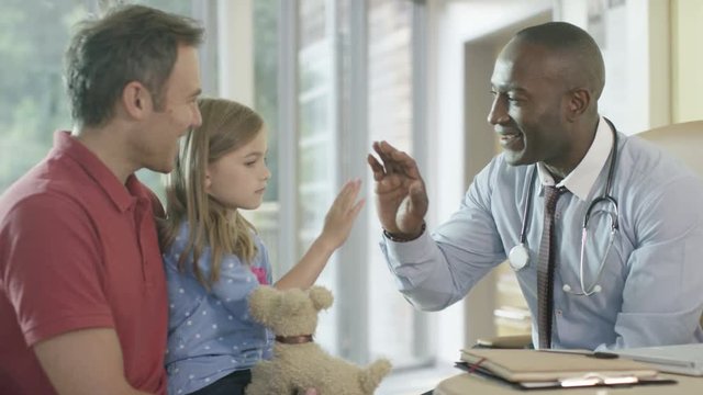  Friendly doctor talking to parent and child patient in office