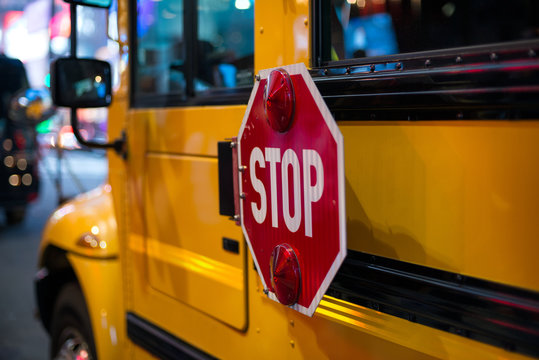 Stop sign on side on yellow School Bus.