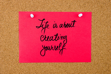 Red paper note with handwritten text on cork board