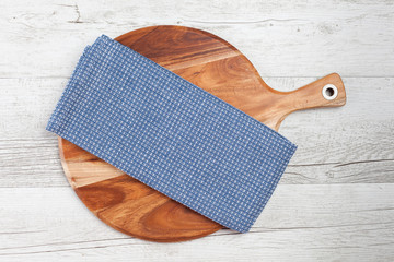 Blue napkin on round chopping board on white rustic wooden table. Top view with copy space