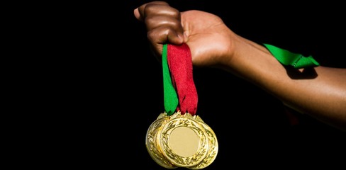Hand holding three gold medals on white background