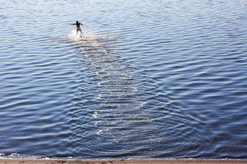 Active man running to swim in lake with reflection
