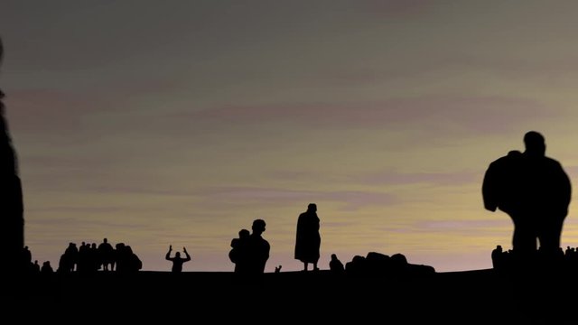 The concept of refugee. Silhouette of the refugees on the border fence with barbed wire at sunset graphics