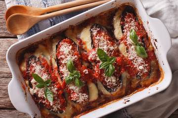 Italian eggplant baked with cheese in tomato sauce close up in baking dish. horizontal top view

