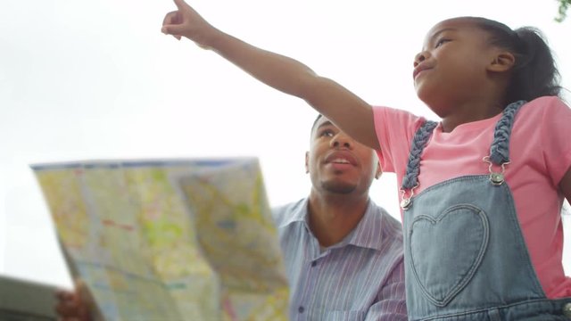  Happy father with daughter sightseeing in London, looking at map for directions. 