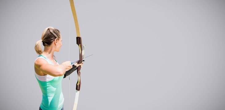 Composite image of rear view of sportswoman practising archery 
