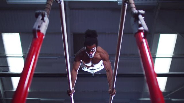  Professional male gymnast training on parallel bars at the gym.