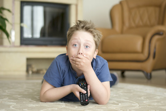 white boy lying on the floor and turning on the TV with remote