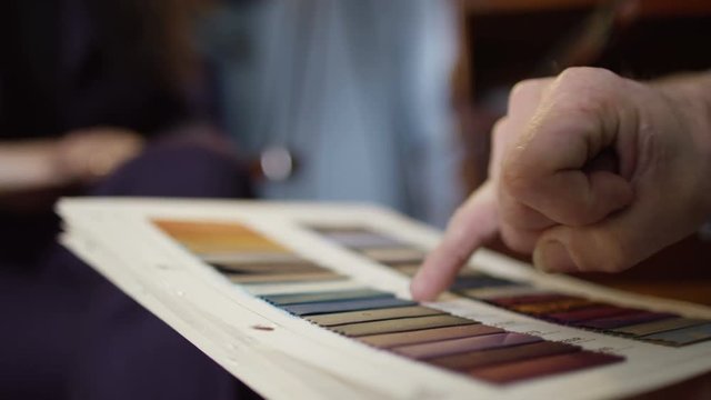  Female client in meeting with tailor looking at fabrics for bespoke outfit